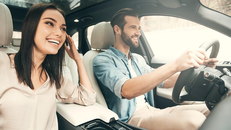 Image of a man driving a car with a woman on the passenger seat beside him.